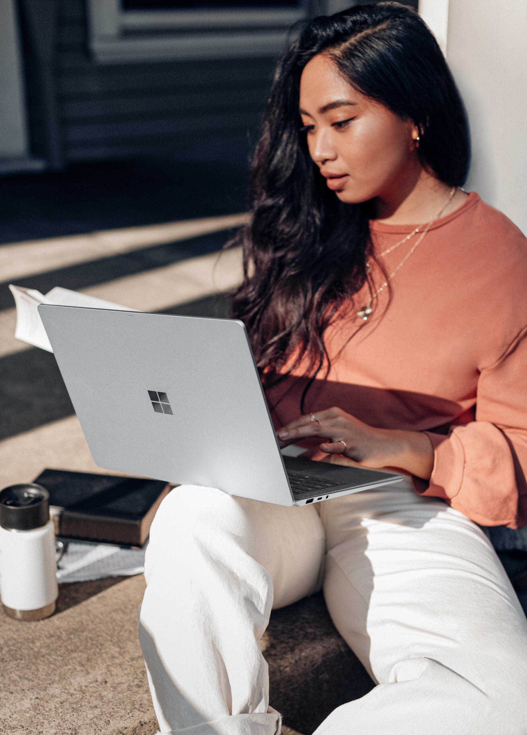 Young woman with Microsoft windows laptop on lap and sitting outside.