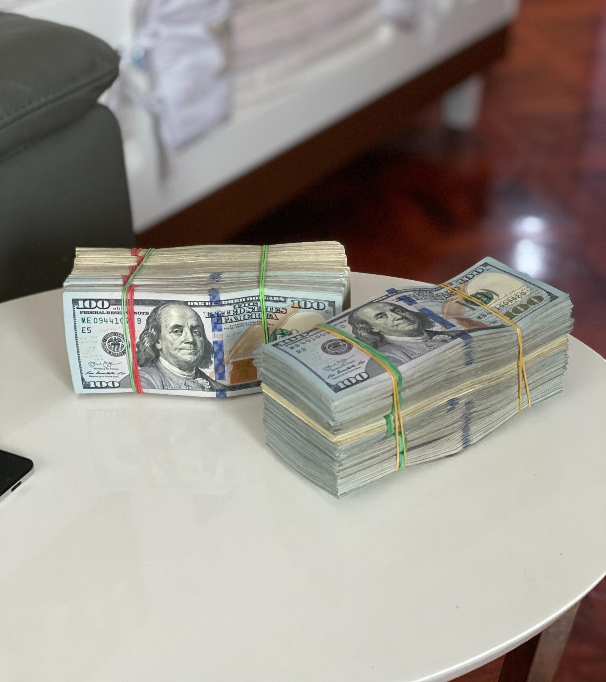 Two stacks of cold hard United States dollars on a white table in a fancy room.